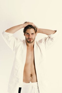 Adam beyaz kimono poz kasları gösterdi. Spor ve stil kavramı. Adam kendinden emin yüz ve kıl