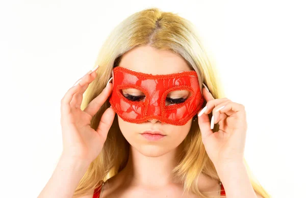 Woman on mysterious face play role game, visit masquerade. Girl with long blonde hair wears mask. Lady with long white manicure hold mask on face, white background, isolated. Mysterious woman concept