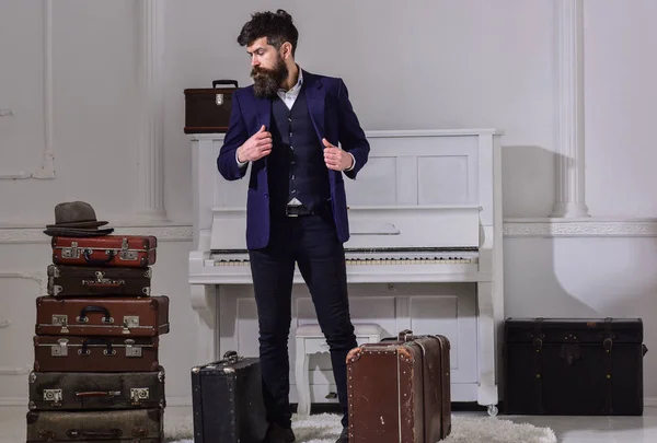 Gepäck und Reisekonzept. Macho-Styling auf nachdenklichem Gesicht, das neben einem Stapel Vintage-Koffer steht. Mann, Reisender mit Bart und Schnurrbart mit Gepäck, luxuriöser weißer Innenraum — Stockfoto