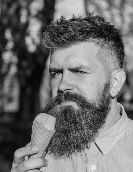 Conceito arrepiante. Homem com longa barba refrigerando com cone de sorvete no dia quente ensolarado, de perto. Homem com barba e bigode no rosto calmo come sorvete, fundo da natureza, desfocado — Fotografia de Stock