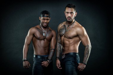 Machos with muscular tattooed torsos look attractive, dark background. Masculinity concept. Guys sportsmen with sexy muscular torsos. Athletes on confident faces with nude muscular chests clipart