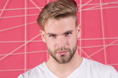 Katı konsantre yüzlü, pembe arka planda kıllı bir adam. Erkeklik kavramı. Sakallı ya da traşsız adam yakışıklı ve bakımlı görünüyor. Sakallı ve çekici bir adam.