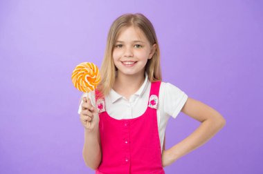 Bir gülücük ver lolipop menekşe arka plan ile. Mor arka plan girdap karamel ile mutlu bir çocukluk. Stick şeker ile gülümseyen küçük çocuk. Yemek ve tatlı. Lolipop gibi tatlı. Beslenme ve diyet