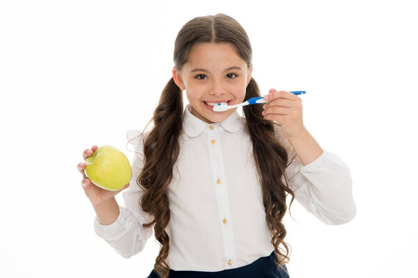 Oral hygiene. Girl cute holds toothbrush and apple white background. Child girl holds apple and brush tooth with paste. Child school girl smart kid happy face cares hygiene. Brush teeth concept