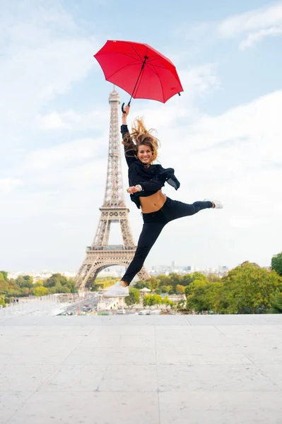 Mulher de moda salto com guarda-chuva. Uma mulher feliz viaja em Paris, na França. Menina com beleza olhar para a torre eiffel. Viajar e vaguear. Parisiense isolado em fundo branco. Desfrute de férias de verão — Fotografia de Stock