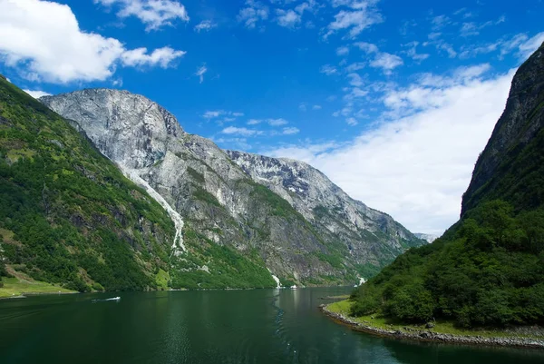 Gemili ya da turistik tekneli uçurumlar arasındaki su. Nehir gölü ve yüksek taşlı dağlar büyüleyici doğa cazibesi Homerswag. İskandinav macerası. İskandinav güzelliğinde dolaşın