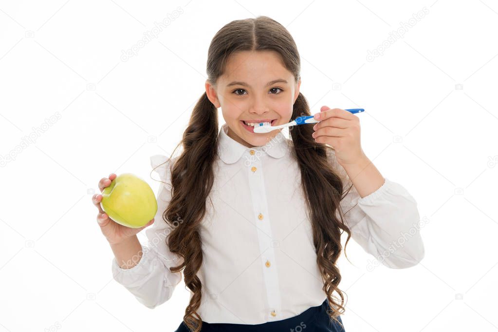 Oral hygiene. Girl cute holds toothbrush and apple white background. Child girl holds apple and brush tooth with paste. Child school girl smart kid happy face cares hygiene. Brush teeth concept