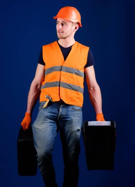 Kask, kask içinde adam araç kutusu ve araç, mavi arka plan ile bavul tutar. Profesyonel tamirci kavramı. Tamirci, tamirci rüya gibi yüzüne gider ve profesyonel ekipman ile çanta taşır