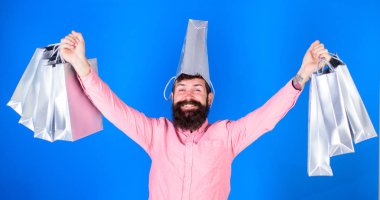 Uzun sakallı ve komik bakmak üzerinde mavi arka plan izole olan adam. Alışveriş mevsimlik satış sırasında trendy sakallı hippi bonkör. Gümüş çanta tutarak ve yorgunluk bir şapka olarak mutlu sakallı adam