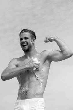 Adam gülüyor ve kasları Berrak gökyüzü arka plan üzerinde gösterilen kıl. Adam gülüyor ve kas gösterilen kıl ile