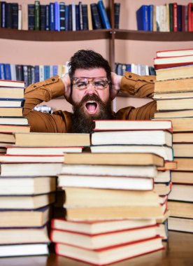 Bilimsel bir keşif kavramı. Öğretmen ya da öğrenci sakallı gözlük takmaz, defocused kitaplar ile masada oturur. Adam kazık kitap kütüphane, kitap rafı arka plan üzerinde arasında şok yüzünde