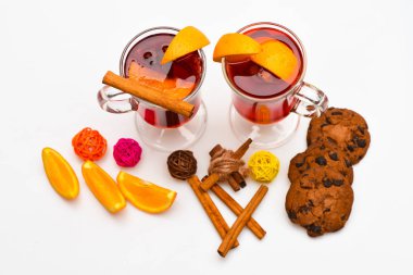 Mevsimlik içecek konsepti. Gözlük mulled şarap veya içki yakınındaki beyaz arka plan üzerinde sulu turuncu meyve ile kapatın. İçki ya da içecek tarçın, portakal meyve ve çikolata damla ile tanımlama