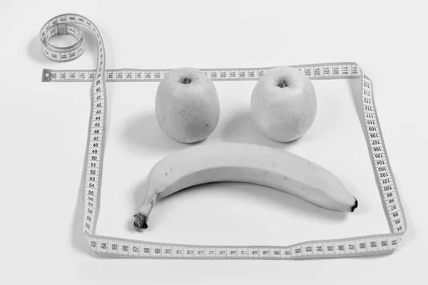Concetto di dieta e salute. Volto di frutta con espressione triste incorniciato con metro a nastro — Foto Stock
