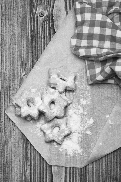 Biscoitos em forma de estrela deitado em pano branco por toalha de cozinha xadrez vermelho. Bolachas de chá em fundo de madeira. Conceito de pastelaria caseira . — Fotografia de Stock