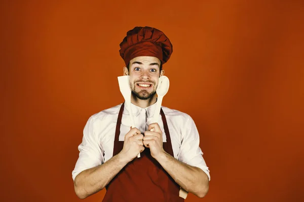 Кухонне начиння та концепція приготування їжі. Шеф-кухар з збудженим обличчям тримає дерев'яну ложку і шпатель — стокове фото