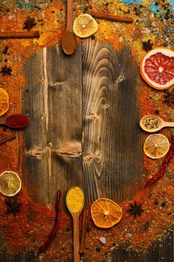 Çeşniler kavramı. Baharatlar ve kuru malzemeler ahşap doku. Tarçın, kırmızı biber ve curcuma dolu kaşık ahşap arka planda, kopya alanı yatıyordu. Tüm yüzey üzerinde dağınık çeşniler