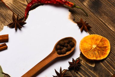 Baharatlar, beyaz kağıt mutfak otlar yatıyordu. Mutfak tarifi kavramı. Tarçın, kurutulmuş portakal ve anasonu lay boş kağıt, tarifi, çevresinde yer kopyalayın. Kağıt ahşap arka plan üzerinde