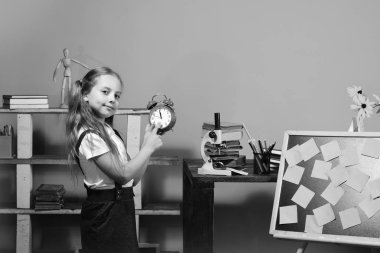 Geri okul ve zaman kavramı çalışma için. Çocuk ve okul malzemeleri, pembe bir arka plan. Mutlu yüz ile kız öğrenci