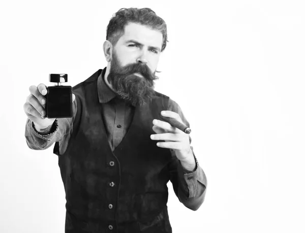 Homme barbu fumant cigare avec un visage sérieux, tenant parfum — Photo