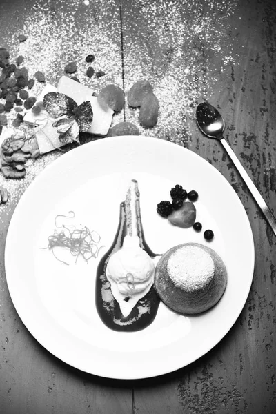 Vit chokladfondant med vaniljglass och jordgubbssås på grå bakgrund. Dessert serveras med torkad frukt i café eller bageri — Stockfoto