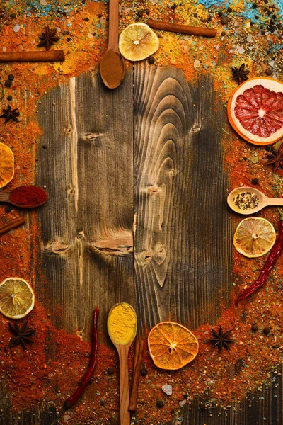 Çeşniler kavramı. Baharatlar ve kuru malzemeler ahşap doku. Tarçın, kırmızı biber ve curcuma dolu kaşık ahşap arka planda, kopya alanı yatıyordu. Tüm yüzey üzerinde dağınık çeşniler