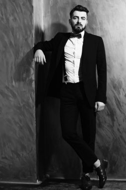 Stüdyo duvarında ciddi bir yüzü olan sakallı bir adam.