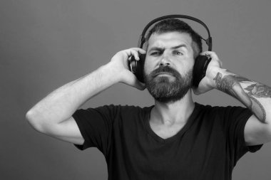 Adam kulaklık mavi arka plan üzerinde tutar. Sakallı DJ kulaklık takıyor. Müzik, parti ve eğlence kavramı.