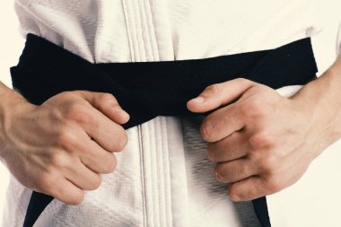 Erkek gövde ve beyaz arka plan üzerinde sportif silah. Adam teşkil etmektedir siyah kemer ile beyaz kimono yakın çekim.