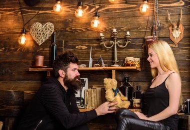 Gülümseyen yüzler üzerinde aşık çift tatilin keyfini çıkarın. Çift gamekeepers evde, ahşap iç arka plan romantik akşamın. Adam Bayan oyuncak ayı için yıldönümü hediye olarak vermek. Yıldönümü kavramı