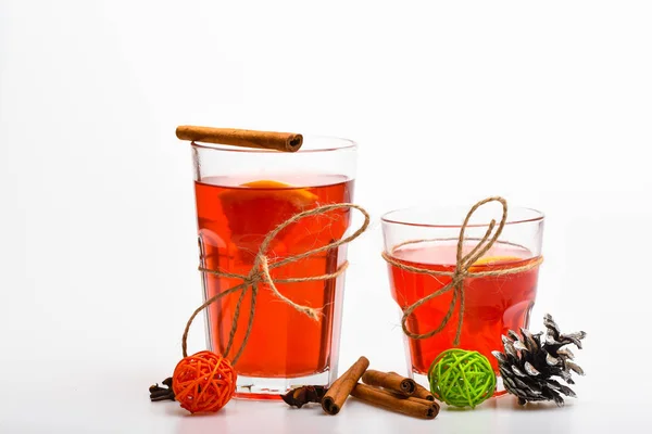 Gläser mit Glühwein oder Heißgetränk mit Bindfäden auf weißem Hintergrund, in Großaufnahme. Weihnachtsgetränke. Glühwein oder Heißgetränk in Gläsern mit Zimtstangen und Tannenzapfen — Stockfoto