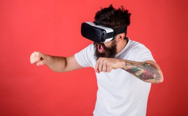 Hippi heyecanlı yüzündeki sürüş hızlı Bisiklet sanal gerçeklik ile modern dijital becerikli alet. Sanal sürüş dersleri kavramı. Vr sakallı sürüş motosiklet, kırmızı arka plan gözlük
