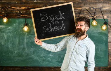 Lise kavramı. Adam sakal ve bıyık neşeli yüzü memnuniyetle öğrencilerin, kara tahta arka plan ile. Gözlük öğretmen okul için başlıklı yazı tahtası tutar.