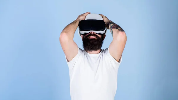 3D design concept. Architect or engineer with virtual reality glasses. Man with beard in VR glasses pleased and delighted, light blue background. Guy in helmet works as engineer in virtual reality