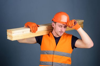 Güvenlik ve koruma kavramı. Marangoz, woodworker, meşgul yüz taşıdığı ahşap kiriş omuz üzerinde güçlü Oluşturucu. Koruyucu eldiven erkekte koruyucu baret, gri arka plan güneşlik tutar