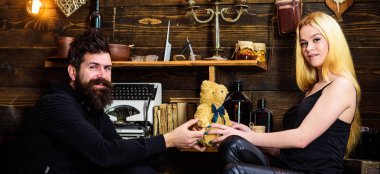 Adam Bayan oyuncak ayı için yıldönümü hediye olarak vermek. Gülümseyen yüzler üzerinde aşık çift tatilin keyfini çıkarın. Çift gamekeepers evde, ahşap iç arka plan romantik akşamın. Yıldönümü kavramı