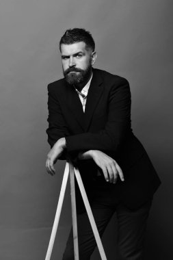 Sakal ve bıyık şık giyer Klasik takım elbise olan adam. Maço erkek fotoğraf makinesi tripod üzerinde kırmızı bir arka plan üzerinde eğilir