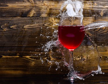 Bardağı su koyu ahşap zemin fışkırmaları ile doldurma. Cam şarap dökme sıvı sıçraması ve su damlaları ile. Serinletici içecek konsepti