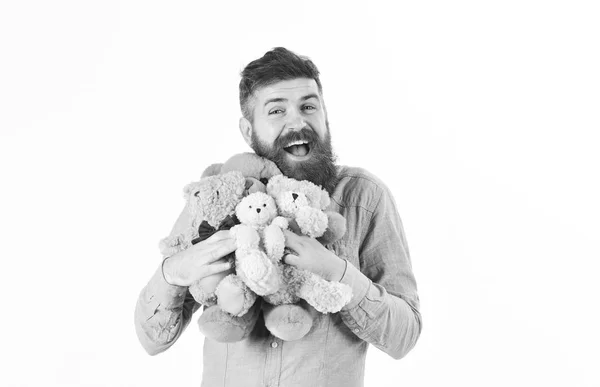 Ragazzo con la barba abbraccia giocattoli morbidi con tenerezza. L'uomo con il viso felice tiene orsacchiotti o peluche — Foto Stock