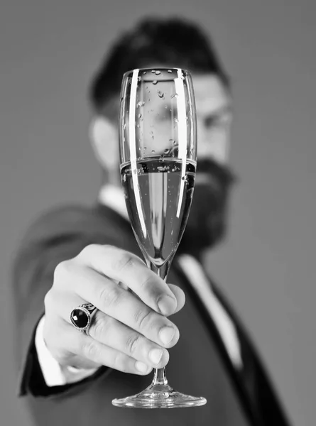 El hombre de negocios con la cara desenfocada tiene vino espumoso. Los gerentes sostienen la copa de champán de cerca. Hombre de traje elegante sobre fondo azul. Negocios y celebración —  Fotos de Stock