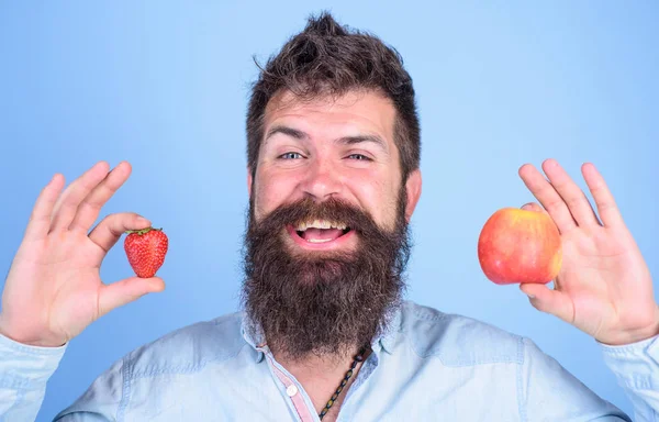 Sakallı adam gülen elma ve çilek eller mavi arka planda tutar. Vitamini meyve beslenme kavramı. Vitamini diyet sağlık. Meyve ve meyve eller sağlıklı alternatif. Yaz aylarında faydaları