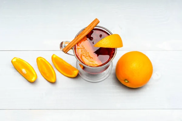 Glas med glögg eller varm cider nära juicy orange frukt på vit bakgrund. Drink eller dryck med apelsin och kanel. Cocktail Bar koncept. Glögg nära skivor av orange, top view — Stockfoto