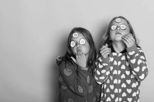 Gyermekek büszke arcok, uborka, a szem és a laza haj. Lányok a színes polka pöttyös pizsama küld csókok — Stock Fotó
