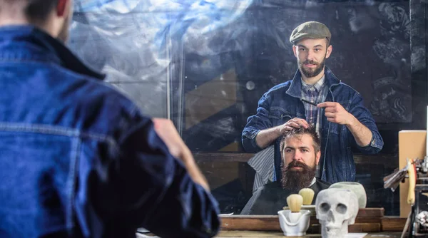 Mannen med skägg och mustasch i frisörer stol framför spegeln bakgrund. Reflexion av Frisör styling hår av skäggiga klient med kam. Barbershop koncept. Hipster-klienten att få frisyr — Stockfoto