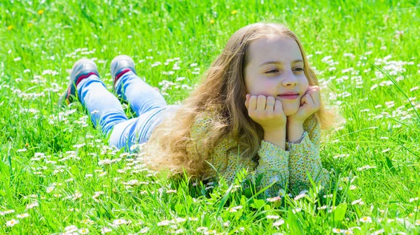 草地、緑色背景で草の上に横たわる少女。子は、草原に横たわっている間春の天候の良い日をお楽しみください。春のコンセプトです。笑顔騎乗過ごすレジャー アウトドア — ストック写真