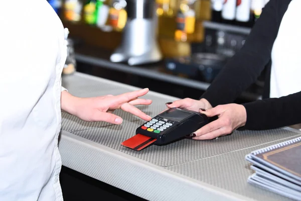 Caixa mão detém terminal de cartão de crédito em fundo desfocado — Fotografia de Stock