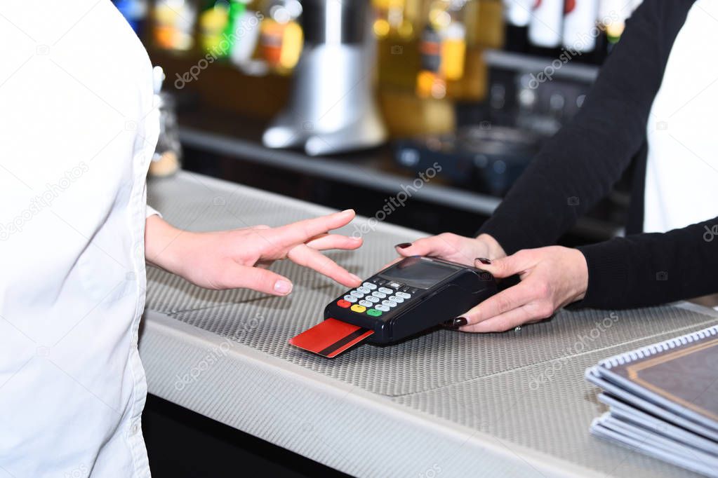 Cashiers hand holds credit card terminal on defocused background
