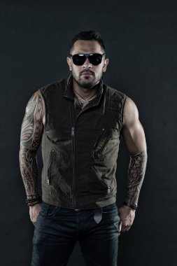 Tıraşsız yüzündeki sakallı dövme modeli. Güçlü silah dövme sakallı adam. Pazı ve triceps dövmeli adam. Moda maço trendy güneş gözlüğü. Moda stil ve trend, vintage filtre