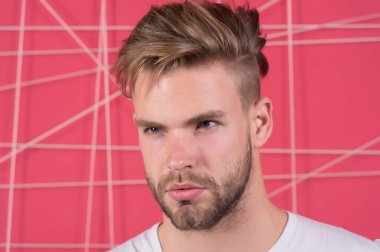 Katı konsantre yüzlü, pembe arka planda kıllı bir adam. Erkeklik kavramı. Sakallı ve çekici bir adam. Sakallı ya da traşsız adam yakışıklı ve bakımlı görünüyor.