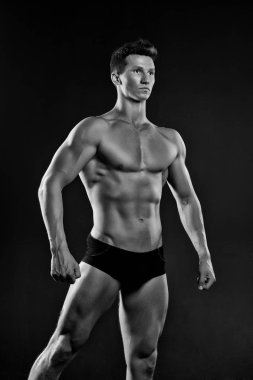 Siyah arka plan üzerine izole vücut geliştiricisi. Kas vücut siyah mayosuyla... adam. Atlet ile seksi bakmak için rekabet, spor kavram hazırlanıyor. Resim için poz kusursuz bir beden ile model