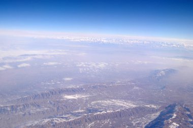 Dünya yüzeyinin üzerinde mavi gökyüzü, havadan görünümü. Çevre koruma ve ekoloji. Dağ manzarası. Yolculuk tutkusu ve seyahat. Yeryüzü cenneti